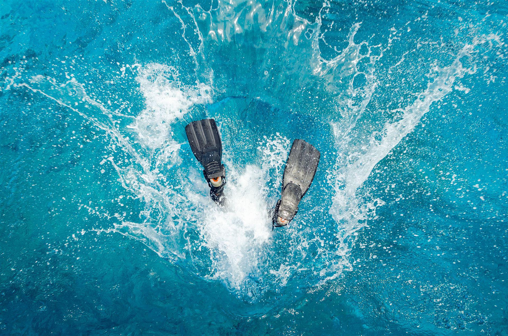 Taucherflossen noch sichtbar über der Wasseroberfläche nach Eintauchsprung ins Wasser 